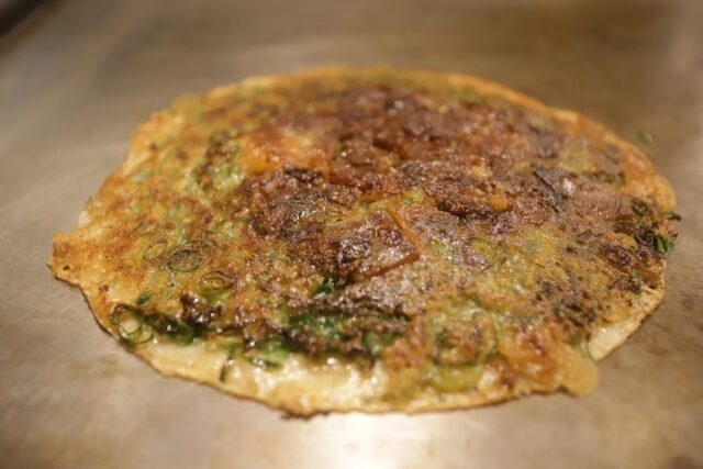 Golden okonomiyaki on a griddle at Misaku Kobe-Kitano-ten