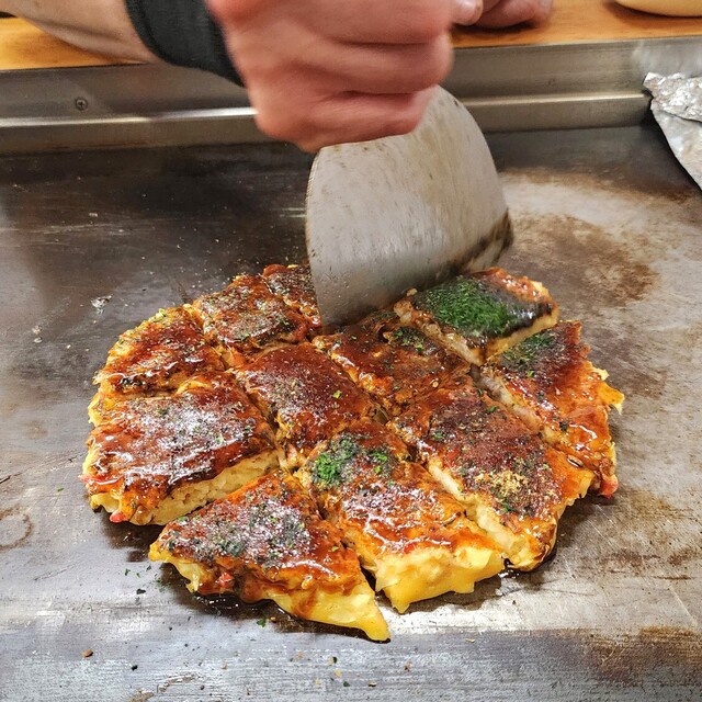 Okonomiyaki being cut with a spatula at Kona