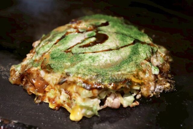 Okonomiyaki topped with sauce and seaweed at Mizuno