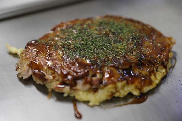 Okonomiyaki topped with sauce at Fuji
