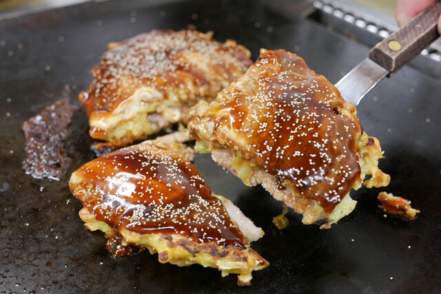 Sliced okonomiyaki on a griddle at Okonomiyaki Chigusa